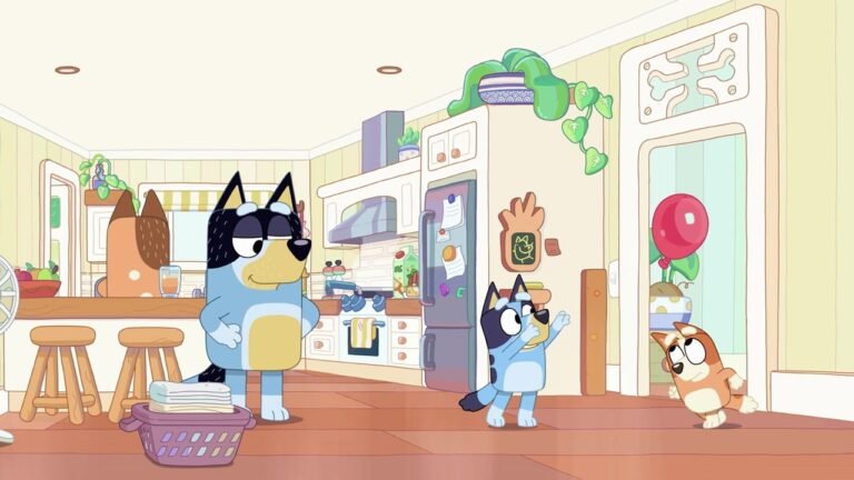 From the Bluey episode 'Keepy Uppy': Bandit stands in the kitchen with a laundry basket, Bluey gestures excitedly, and Bingo peeks from the doorway with a red balloon visible behind her.